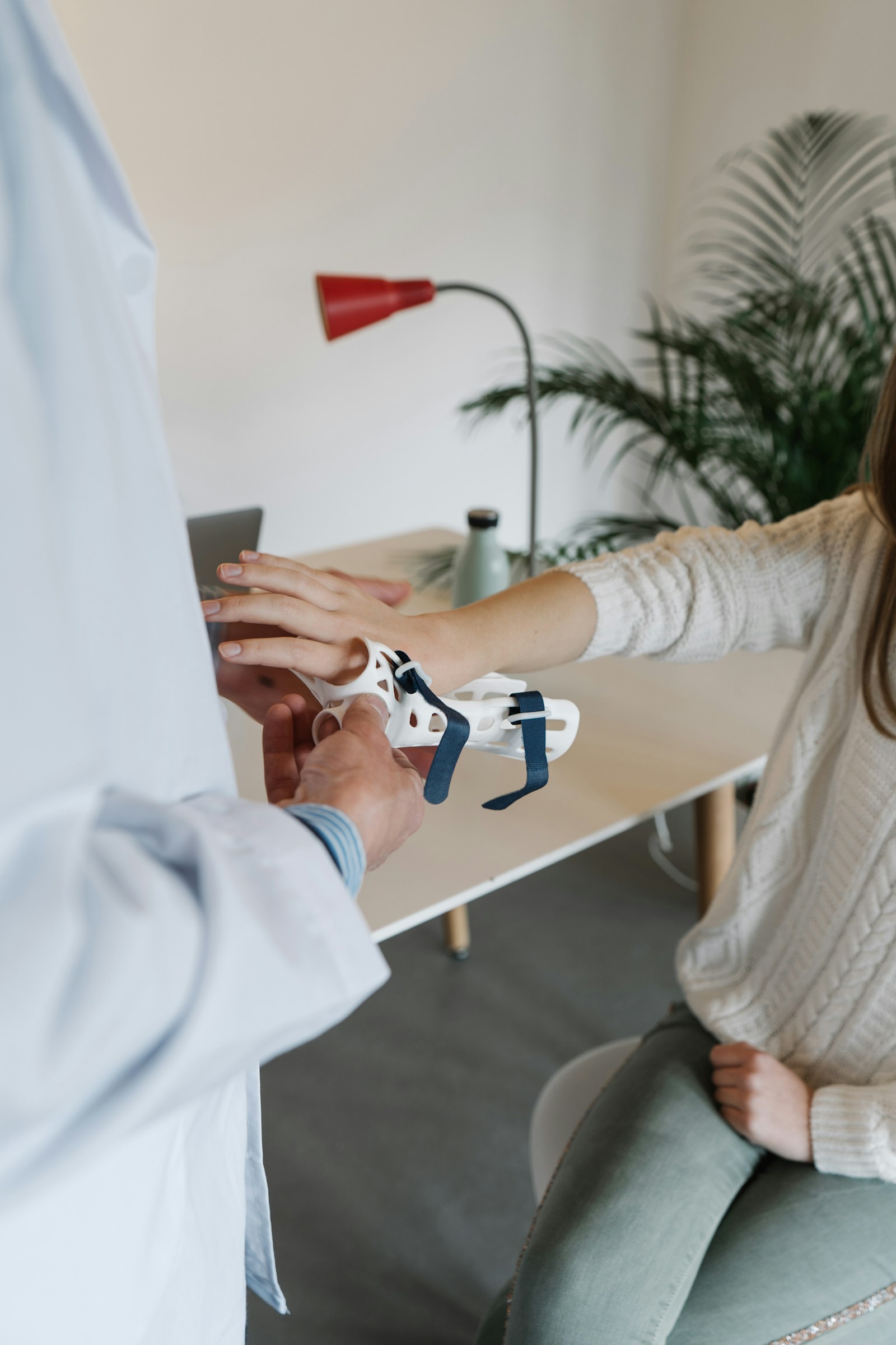 اختصاصي يركّب دعامة بيضاء مخصّصة للرسغ حول يد المريض وساعده