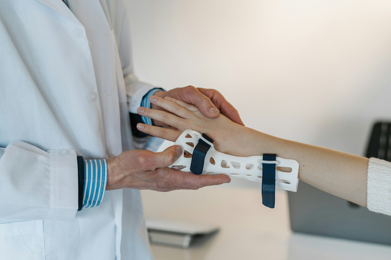 Close-up of a clinician supporting a patient’s wrist while checking a fitted hand and forearm brace